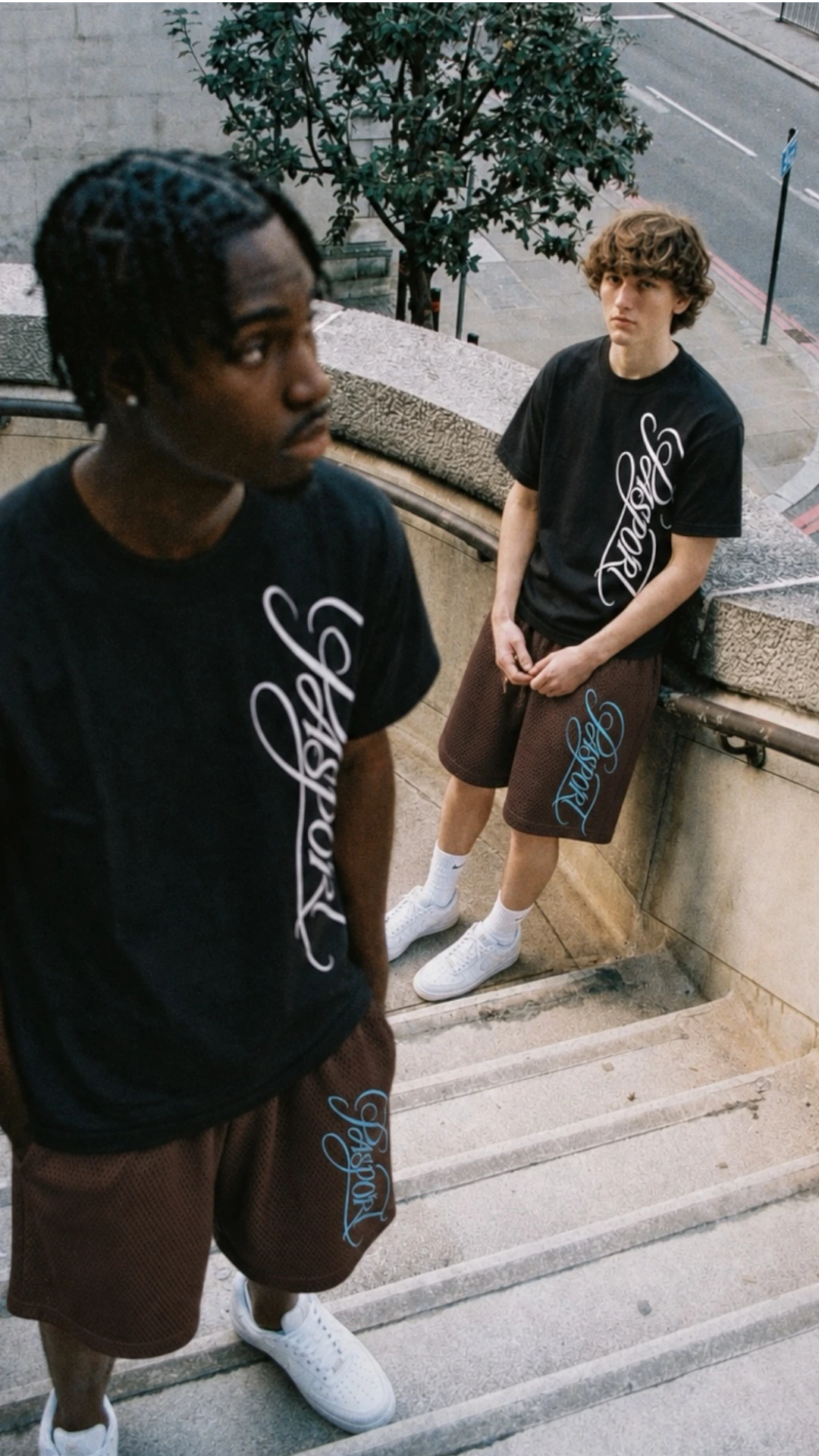 Black graphic tees and brown mesh shorts on urban steps